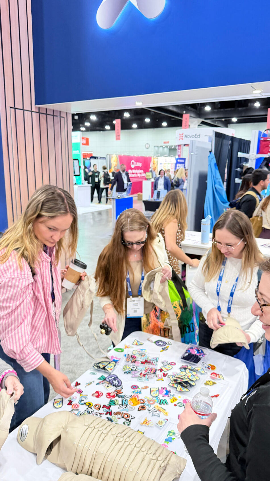 Guests at a convention picking embroidered patches and letters from a table covered in colourful options